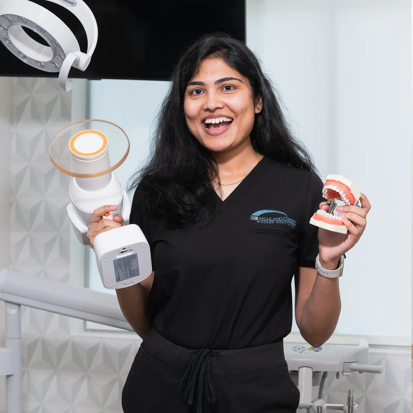 Highland Creek Modern Dentistry holding a tool and a denture